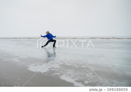 Caucasian woman in a blue sweater skating on a frozen lake. Caucasian woman in a blue sweater skating on a frozen lake. 109189850