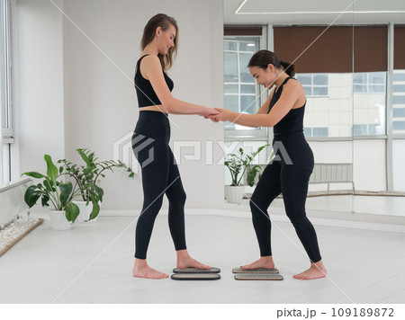 Caucasian and Asian women stand up sadhu boards together.  109189872