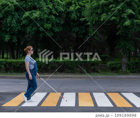 Blind pregnant woman crosses the road at a crosswalk with a cane. Blind pregnant woman crosses the road at a crosswalk with a cane. 109189898