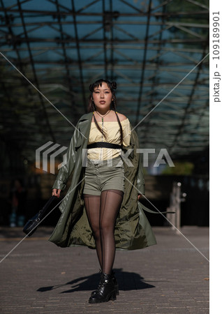 A beautiful Asian woman in shorts and a green leather coat comes out of the subway. A beautiful Asian woman in shorts and a green leather coat comes out of the subway. 109189901