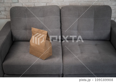 Kraft paper bag with food delivery on gray sofa. Kraft paper bag with food delivery on gray sofa. 109189908
