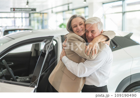 Mature Caucasian couple hugging. Elderly man and woman buying a new car. Mature Caucasian couple hugging. Elderly man and woman buying a new car. 109190490