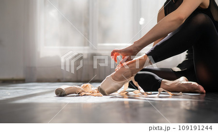 Faceless ballerina sits on the floor and puts on pointe shoes. Faceless ballerina sits on the floor and puts on pointe shoes. 109191244