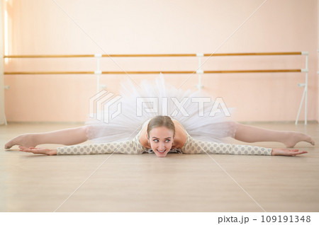 Beautiful ballerina in body and white tutu is training in a dance class. Young flexible dancer posing in pointe shoes sitting on the floor. Beautiful ballerina in body and white tutu is training in a dance class. Young flexible dancer posing in pointe shoes sitting on the floor. 109191348