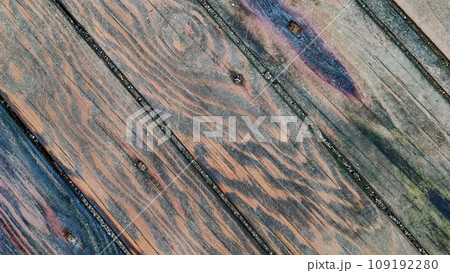 Background of wooden surface made of boards with multicolored spots from humidity, diagonal lines, top view, close-up. 109192280