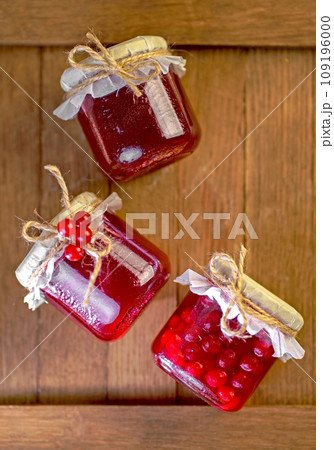 viburnum jam. Red juicy berries of a viburnum with sugar in a glass jar on a dark wooden background. For making jam, tea. Medicinal plant. 109196000