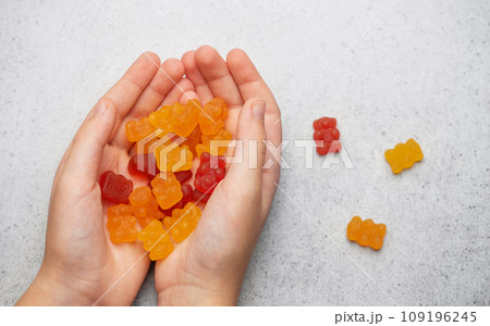 A girl holds a gummy bear vitamines in her hands 109196245