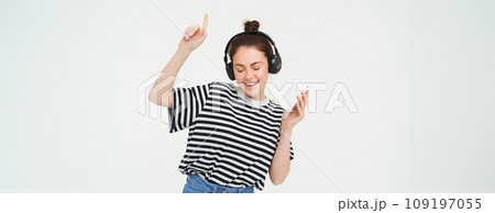 Portrait of happy brunette woman, dancing in headphones, listening music on her mobile app, enjoys her favorite song, isolated against white background Portrait of happy brunette woman, dancing in headphones, listening music on her mobile app, enjoys her favorite song, isolated against white background 109197055