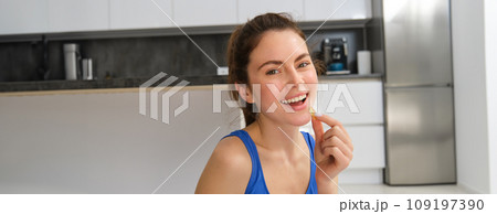 Image of young woman, sporty fitness girl taking vitamins, dietary supplements for muscles strength, sitting on yoga mat and workout 109197390