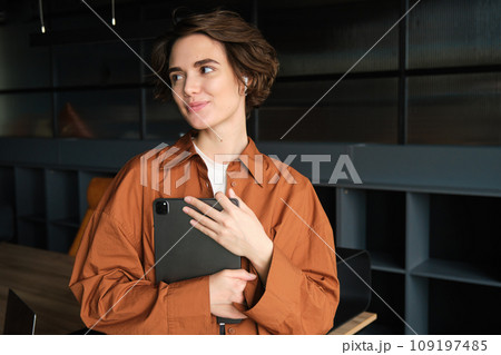 Portrait of young woman, company employee, office worker in casual clothes working with tablet in conference room, planning team meeting 109197485