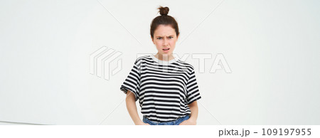 Image of bothered, disappointed young woman, frowning, complaining, looking angry and upset, standing over white background, arguing Image of bothered, disappointed young woman, frowning, complaining, looking angry and upset, standing over white background, arguing 109197955