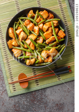 Pad Prik King chicken and crunchy long beans tossed in salty-sweet red curry paste closeup on the plate. Vertical top view 109198613