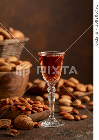 Italian liqueur Amaretto with almonds nuts on a brown background. Italian liqueur Amaretto with almonds nuts on a brown background. 109200791
