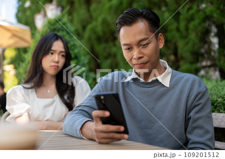 Young Asian girlfriend getting upset at her boyfriend for not paying attention to her. 109201512