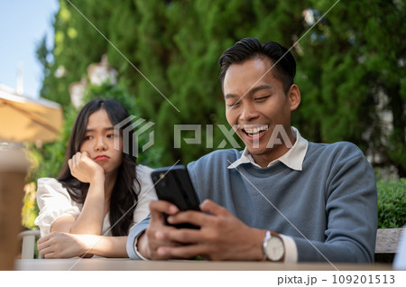 Young Asian girlfriend getting upset at her boyfriend for not paying attention to her. Young Asian girlfriend getting upset at her boyfriend for not paying attention to her. 109201513