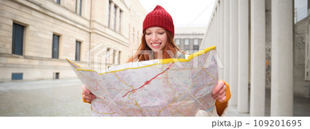 Redhead girl, tourist explores city, looks at paper map to find way for historical landmarks, woman on her trip around euope searches for sightseeing 109201695
