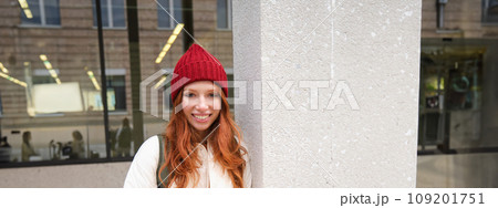 Beautiful redhead girl with smartphone, standing on street, holding mobile phone, using taxi app, connects to public wifi and uses internet, sends a text message 109201751