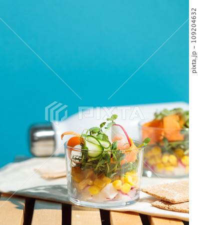 healthy salad in a glass cup. Pieces of fresh vegetables, micro-greens and corn. Close-up, aesthetics. 109204632