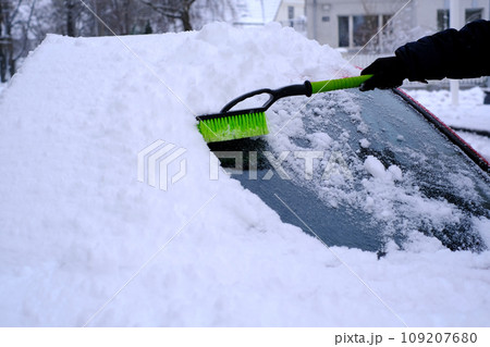 Snow cleaning from car with a brush in close-up 109207680