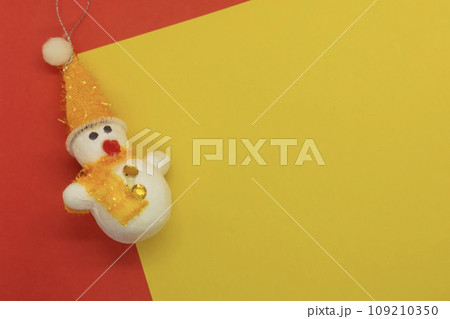 Snowman and Christmas decoration on yellow and red background with copy space Snowman and Christmas decoration on yellow and red background with copy space 109210350
