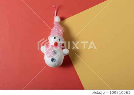 Christmas snowman toy on red and yellow background with copy space for text. 109210363