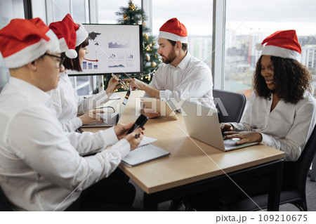 Multiethnic diverse business colleagues in Santa hats at meeting in office 109210675