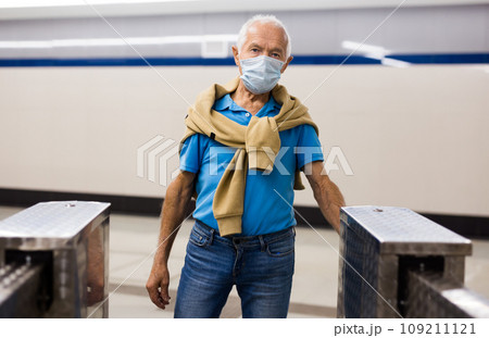 Elderly passenger in protective mask pays for a metro ride using mobile phone Elderly passenger in protective mask pays for a metro ride using mobile phone 109211121