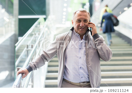 Elderly passenger talking on mobile phone at an underground metro station Elderly passenger talking on mobile phone at an underground metro station 109211124