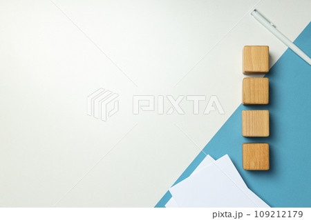 Wooden cubes, papers and pen on white and blue background, space for text Wooden cubes, papers and pen on white and blue background, space for text 109212179