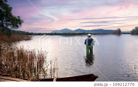 pond landscape in twilight with fisherman fishing on water in vocation day 109212770