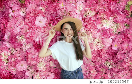 Happy asian woman smiling on pink flower background Happy asian woman smiling on pink flower background 109213547