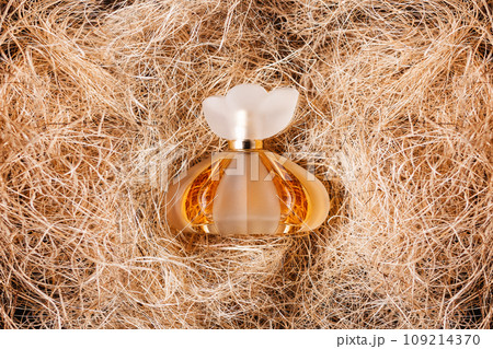A transparent bottle of golden perfume on the hay. Flat lay. The concept of beauty industry and perfumery 109214370