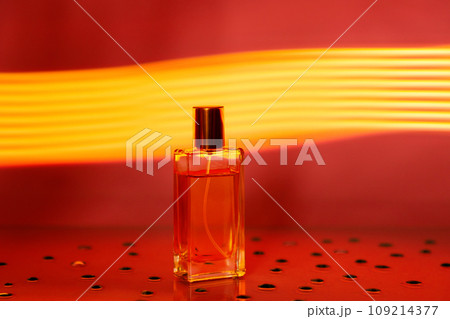 Transparent glass rectangular bottle of perfume on golden neon background. Copy space Transparent glass rectangular bottle of perfume on golden neon background. Copy space 109214377
