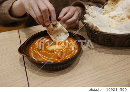 日本のインド料理店で提供されるバターチキンカレーとナンのセット 109214590