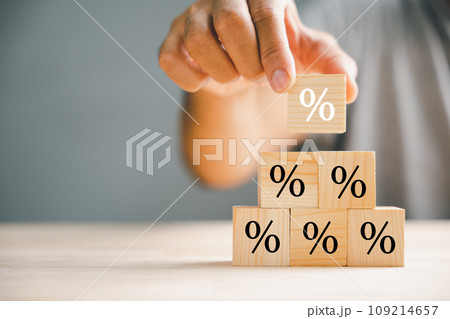 Illustrating the concept of interest rate and financial ranking. Businessman's hand placing a wooden cube block with a percentage symbol icon, representing the dynamic nature of rates. 109214657