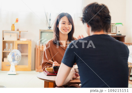 ドラマのようなレトロな雰囲気の食卓でごはんを食べる若い夫婦 109215151