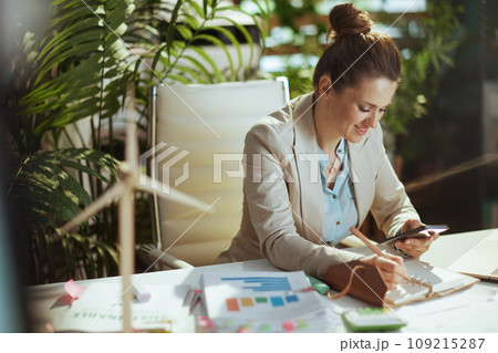 smiling woman employee in green office using phone 109215287