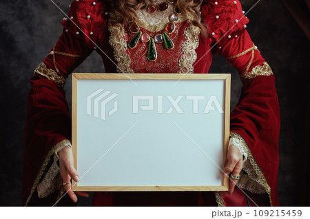 Closeup on medieval queen in red dress showing blank board 109215459