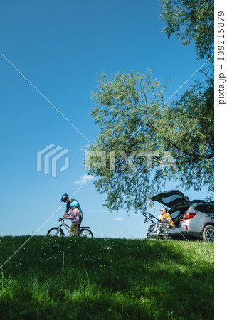 happy family outdoors father teaching daughter yo bicycle mother sitting in car trunk 109215879