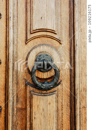 Brown wooden door with brass knocker. Old elegant metal door handle 109216175