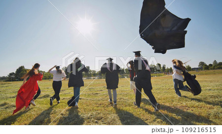 Happy graduates run in and take off their robes. The concept of graduation. Happy graduates run in and take off their robes. The concept of graduation. 109216515