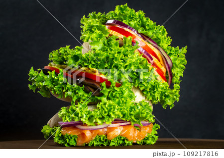 Set of sandwiches in pitas with fresh salmon, ham, vegetables, salad. Homemade sandwiches. Healthy fast food. On a wooden board 109217816