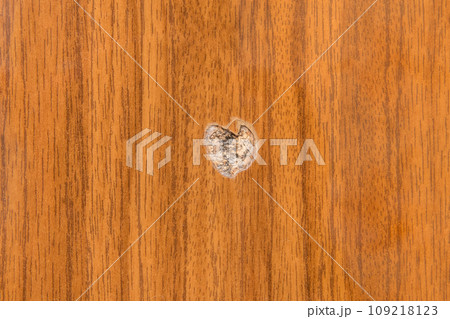 Round hole brown wooden surface broken chipboard material damaged pressed wood, close-up Round hole brown wooden surface broken chipboard material damaged pressed wood, close-up 109218123