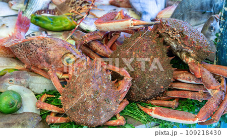 Stall at the Essaouira fish market with a variety of fresh crabs and seafood. Fishermen clean and prepare the catch, offering the coastal traditions that define Essaouira's culinary culture. 109218430