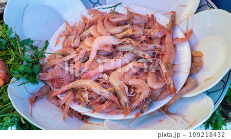 Dish of shrimp at the Essaouira fish market. Fishermen skillfully clean and prepare the catch, offering the coastal traditions that define Essaouira's culinary culture. 109218432