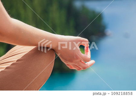 Close-up yoga hands. Woman exercising meditation outdoors nature background. Healthy and Yoga Concept Close-up yoga hands. Woman exercising meditation outdoors nature background. Healthy and Yoga Concept 109218858