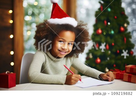 Cute little girl with curly hair in Santa hat writes the letter to Santa Claus 109219882