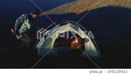 Man sets up tent on top of mountain hill using axe Man sets up tent on top of mountain hill using axe 109220922