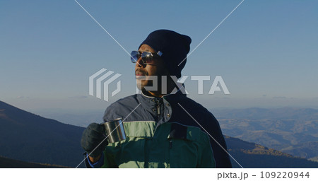 Tourist drinks cup of tea on top of mountain hill 109220944