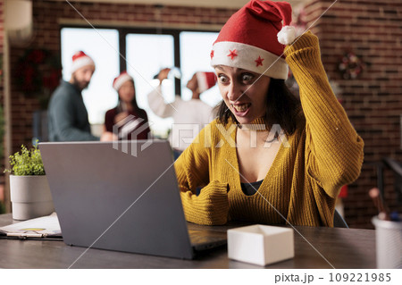 Angry caucasian woman in santa hat having breakdown while working on laptop in office at christmas eve. Furious overworked managing task deadline in workplace during xmas holiday Angry caucasian woman in santa hat having breakdown while working on laptop in office at christmas eve. Furious overworked managing task deadline in workplace during xmas holiday 109221985